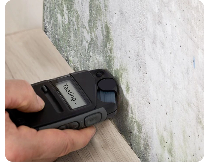 A person using a cordless device to check the wall.