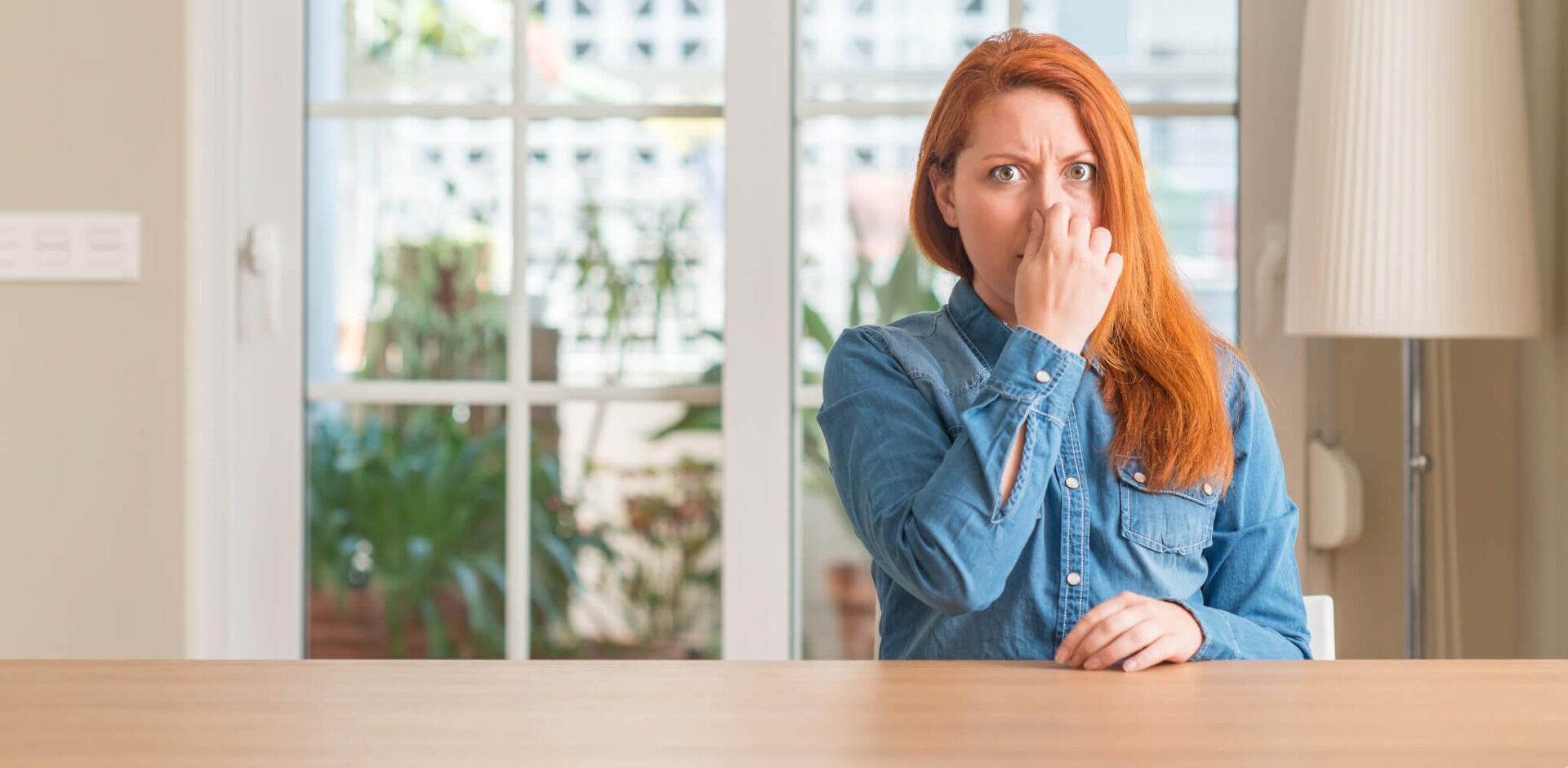 A woman sitting at the table with her hand over her mouth.